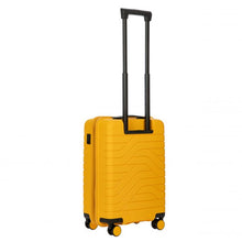 Load image into Gallery viewer, Angled back view of the light blue  hard shell suitcase with black accents. The back panel has a textured wave lines design. The telescopic handle is pulled up.

