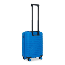 Load image into Gallery viewer, Angled back view of the electric blue hard shell suitcase with black accents. The back panel has a textured wave lines design. The telescopic handle is pulled up.
