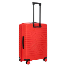 Load image into Gallery viewer, Angled back view of the red hard shell suitcase with black accents. The back panel has a textured wave lines design. The telescopic handle is pulled up.
