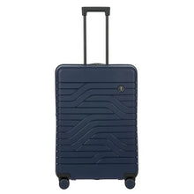 Load image into Gallery viewer, Front view of the navy blue hard shell suitcase with black accents. The panel has a textured wave lines design, and a small black circular logo at the top right. The telescopic handle is pulled up.
