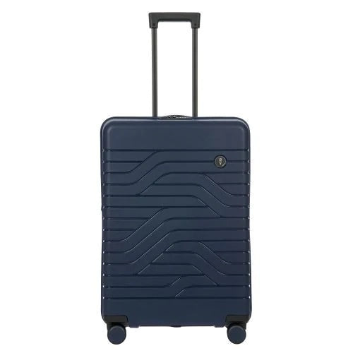 Front view of the navy blue hard shell suitcase with black accents. The panel has a textured wave lines design, and a small black circular logo at the top right. The telescopic handle is pulled up.