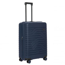Load image into Gallery viewer, Angled front view of the navy blue hard shell suitcase with black accents. The front panel has a textured wave lines design, and a small black circular logo at the top right. The telescopic handle is pulled up.
