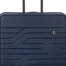 Load image into Gallery viewer, Close up to the top front of the light blue hard shell suitcase. The wave lines design is visible with the circular black BY logo at the top right.
