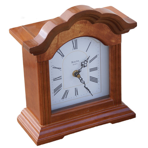 Angled front view of the Bulova Mantle clock. It is made of  warm light brown wood, it has an ivory white face, and roman numerals. 