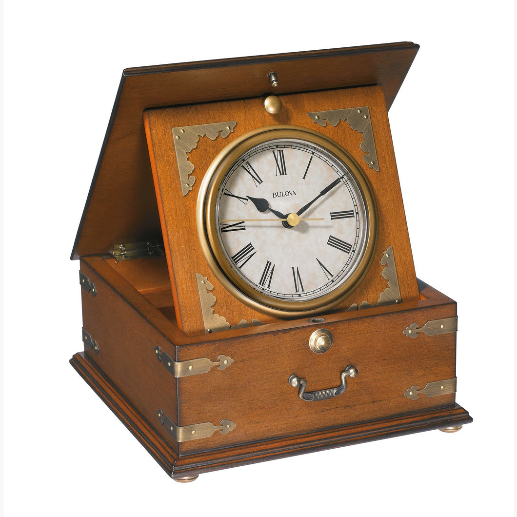 Angled front view of the wooden tabletop clock. It has Roman numerals, and a small drawer handle on the front. 