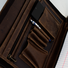 Load image into Gallery viewer, Angled close up to the front interior panel of the pad folio with organizers for documents, cellphones, pens and a zipper-closing pocket.

