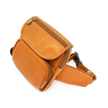 Load image into Gallery viewer, Angled left view of the tan leather hip pack with zipper-closing compartments. 
