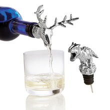 Load image into Gallery viewer, Wine being poured from a blue bottle with a deer head-shaped pourer. A T-Rex shaped pourer is set to the side. 
