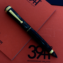 Load image into Gallery viewer, Front view of the fountain pen with the cap on, set on top of the presentation box and red booklet. 
