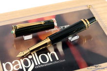 Load image into Gallery viewer, Angle view of the black and green fountain pen with golden accents on top of the presentation box. The cap is set to the pen.
