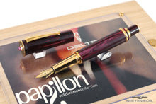 Load image into Gallery viewer, Angled view of the fed fountain pen with golden accents. The cap set next to it. 
