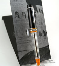 Load image into Gallery viewer, Front view of the ballpoint pen on a stand with a booklet set behind it.
