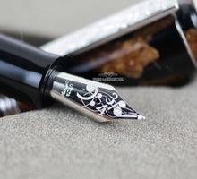 Load image into Gallery viewer, Angled close up to the fountain pen nib with engraved music sheet marking decorations, Delta, 18K-750

