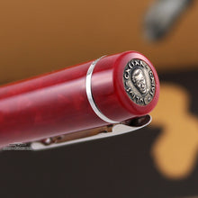 Load image into Gallery viewer, Angled top view of the red pen's round silver disk. It has the face and name of Julius Caesar engraved on it.
