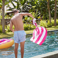 Load image into Gallery viewer, A young man spinning the white and pink stripes towel next to a pool.
