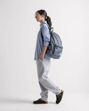 Load image into Gallery viewer, A young woman facing left while carrying a packable daypack backpack. 
