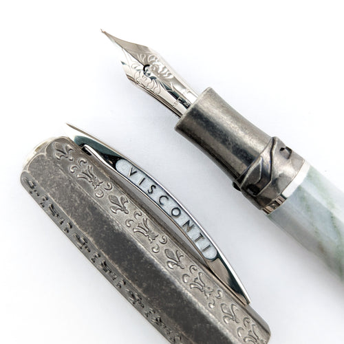 Close up to the Visconti Il Magnifico Green Marble Fountain Pen nib and cap. The nib is made of 18kt white gold and has a series of engraved decorations. The side of the cap's clip has the word VISCONTI engraved on it.