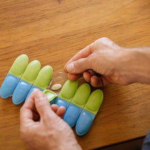 Load image into Gallery viewer, A pair of hands setting a pill inside the Wednesday compartment.
