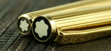 Load image into Gallery viewer, Angled close up to the golden fountain pen's top of the cap, and bottom of the pen barrel. Both feature the Montblanc logo. 
