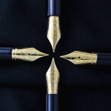 Load image into Gallery viewer, Close up to the four golden nibs engraved with different decorations, Montegrappa logo, and gold hallmarks.
