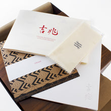 Load image into Gallery viewer, The included booklets, origami paper, and polishing cloth on top of the presentation box.
