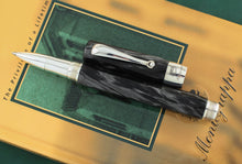 Load image into Gallery viewer, The rollerball  pen arranged with the cap on top of the Montegrappa book.

