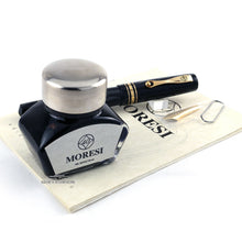 Load image into Gallery viewer, The fountain pen arranged with the ink bottle, extra nib, and booklet.
