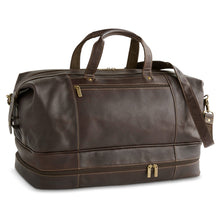 Load image into Gallery viewer, Angled front view of a brown leather duffle bag with zipper-closing compartments. The shoulder strap is resting across the top and front. 
