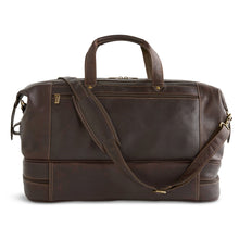 Load image into Gallery viewer, Front view of the brown leather duffle bag. The shoulder strap is resting across the top and front diagonally. 
