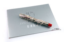 Load image into Gallery viewer, Front view of the fountain pen with the cap on, resting on the booklet. 

