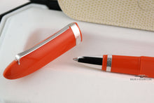 Load image into Gallery viewer, Close up to the orange pen's grip section with the cap next to it.
