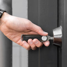 Load image into Gallery viewer, A hand holding a leather key organizer with a stainless steel key ring, trying to unlock a door.
