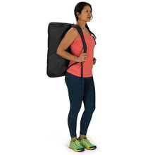 Load image into Gallery viewer, A young woman in a gym outfit carrying the duffle like a backpack.
