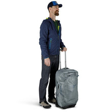 Load image into Gallery viewer, A young man holding the gray wheeled duffle by the telescopic handle.
