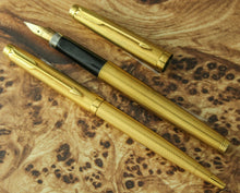 Load image into Gallery viewer, Front view of the two golden pens on a wooden surface.
