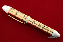Load image into Gallery viewer, Side view of the fountain pen on a red surface. 
