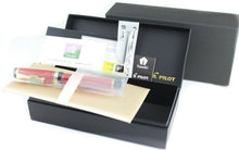 Load image into Gallery viewer, The fountain pen arranged with the included documents, ink cartridge, presentation box and outer box. 
