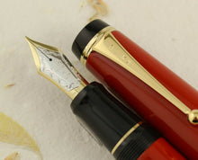 Load image into Gallery viewer, Close-up of a Pilot Custom Vermillion Urushi Fountain Pen with a two-toned 18-karat gold nib, showcasing the red and black barrel with Urushi lacquer finish.
