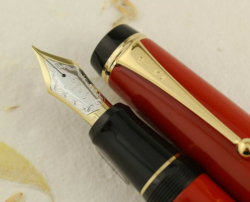 Close-up of a Pilot Custom Vermillion Urushi Fountain Pen with a two-toned 18-karat gold nib, showcasing the red and black barrel with Urushi lacquer finish.