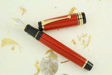 Load image into Gallery viewer, Front view of the red fountain pen with the cap set to the side. 
