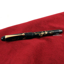 Load image into Gallery viewer, Side view of the fountain pen with the cap on, laid on a soft red surface.
