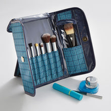 Load image into Gallery viewer, The blue cosmetic brush case unfolded and leaning on the stand. 
