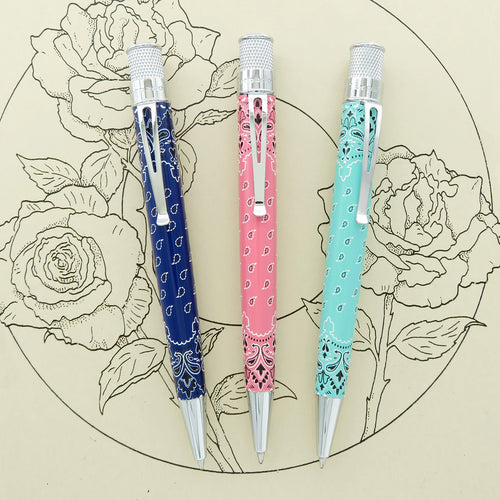 Front views of a navy blue, pink, and aqua set of pens on a background with illustrated roses.