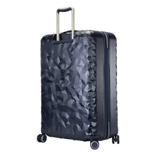 Load image into Gallery viewer, Angled back panel view of the navy blue hard-shell suitcase with geometric texture. 
