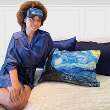 Load image into Gallery viewer, A young woman in a blue robe sitting on a bed with the Starry Night pillow case and matching  eye mask.
