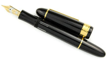 Load image into Gallery viewer, Front view of the fountain pen with the cap set to the side. the grip section has a set of small windows to show the ink color inside the pen. 
