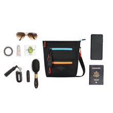 Load image into Gallery viewer, The crossbody bag laid with travel accessories which can fit inside. 
