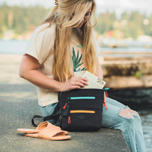 Load image into Gallery viewer, A young girl sliding a book into the bag&#39;s main compartment. 
