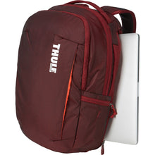 Load image into Gallery viewer, Angled front panel view of the ember red backpack with a laptop peeking from the back panel&#39;s side compartment.
