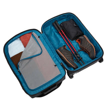 Load image into Gallery viewer, Interior view of the suitcase with travel accessories organized within the panels. 
